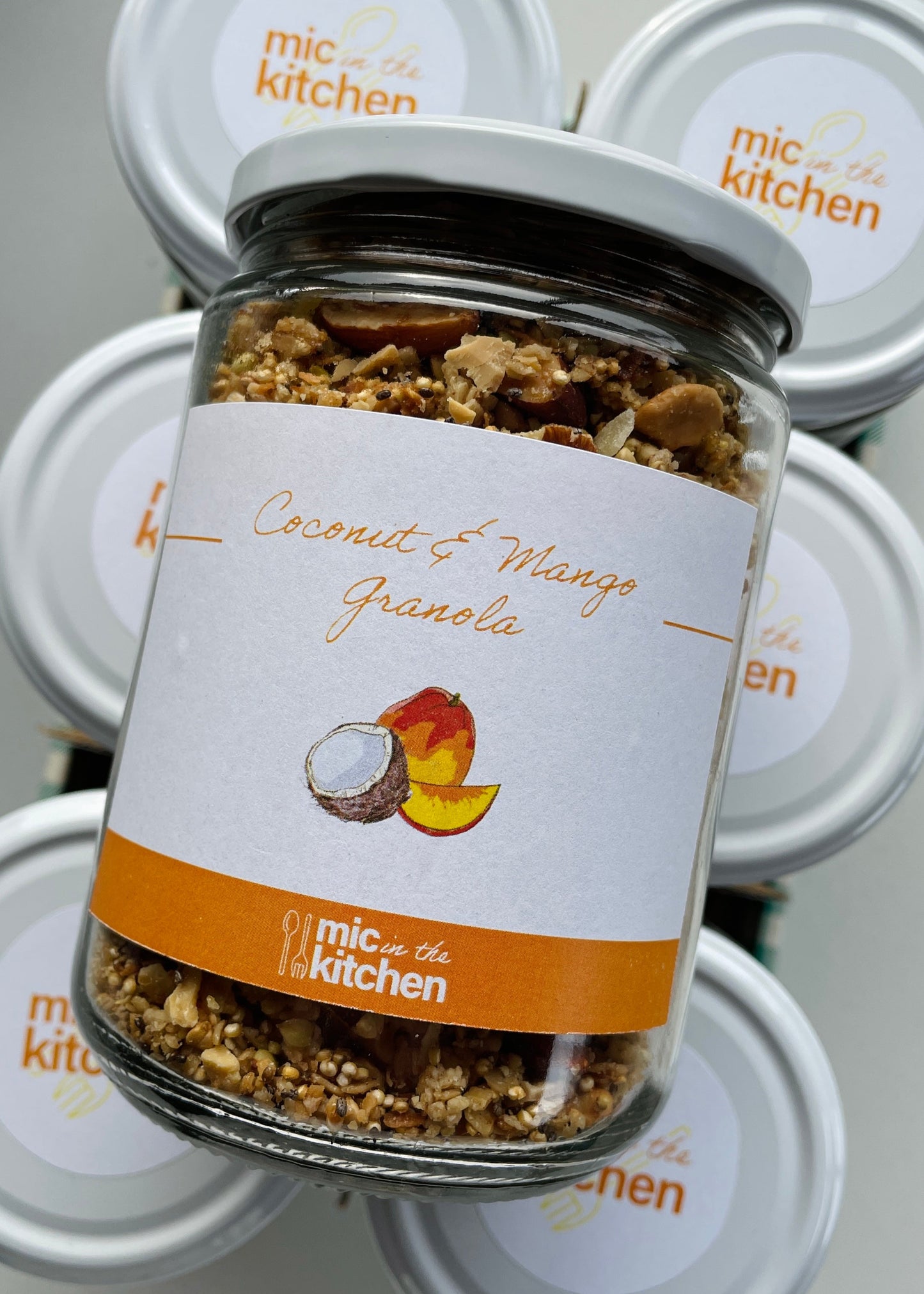 Jar of coconut and mango granola with a label on a white background